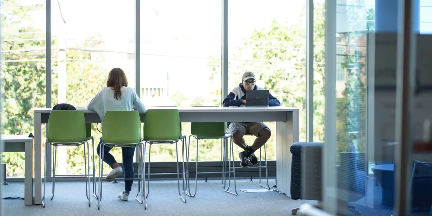 Two students sitting at high table in the club hub