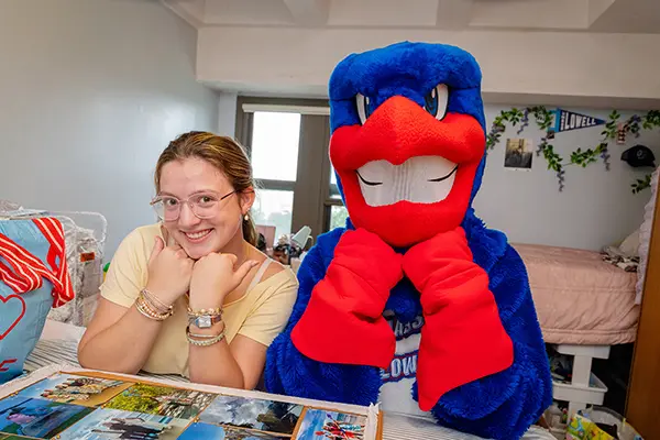 Image shows UMass Lowell mascto Rowdy the River Hawk with first-year student Amelia Johnson of Tyngsboro, Massachusetts, who moved into her room inside Fox Hall in August 2025.