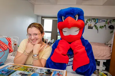 Image shows UMass Lowell mascto Rowdy the River Hawk with first-year student Amelia Johnson of Tyngsboro, Massachusetts, who moved into her room inside Fox Hall in August 2025.