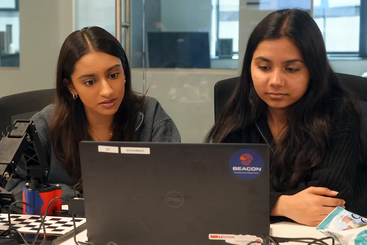 Aadya Gurjar and Vaishnavi Vyas look at a computer.