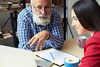 Professor looking over a laptop computer with a student