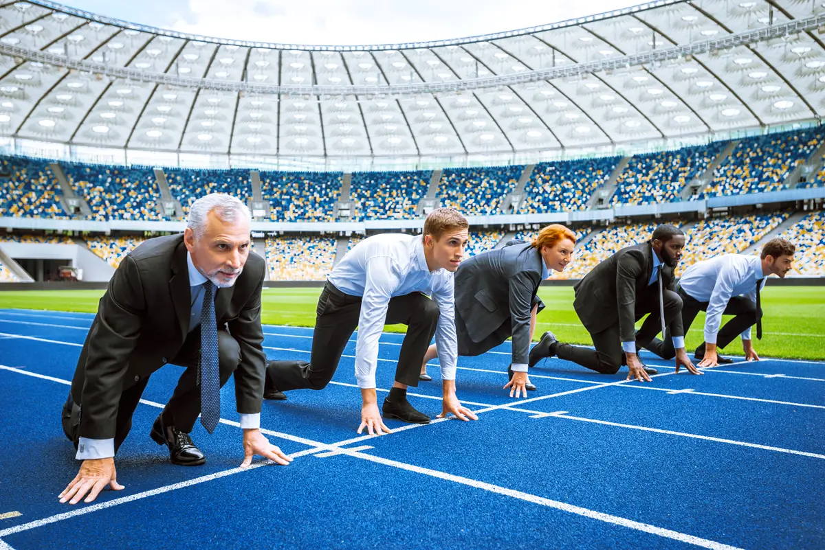 People in business attire on starting line of athletic track in sport arena.