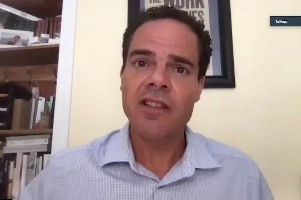 A man talks from his office on Zoom