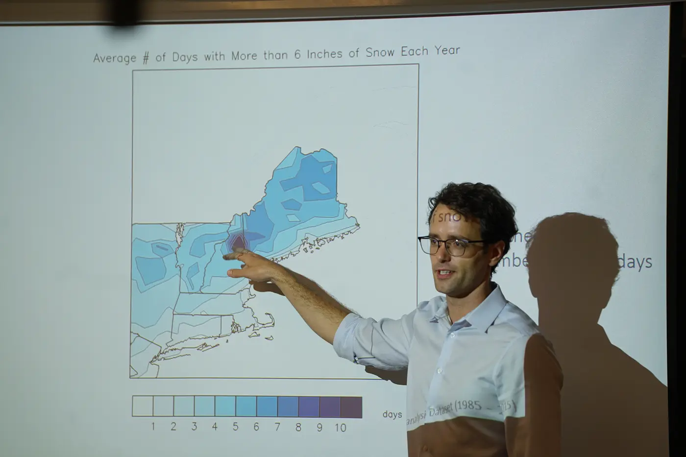 Man presenting in front of map of New England on screen
