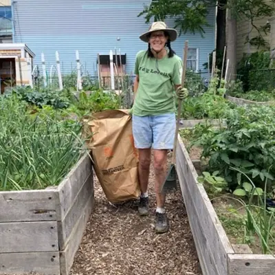 Woman with gardening tools standing amid raised beds