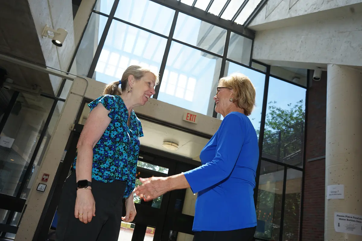 Two women talk while standing in the foyer of a building.