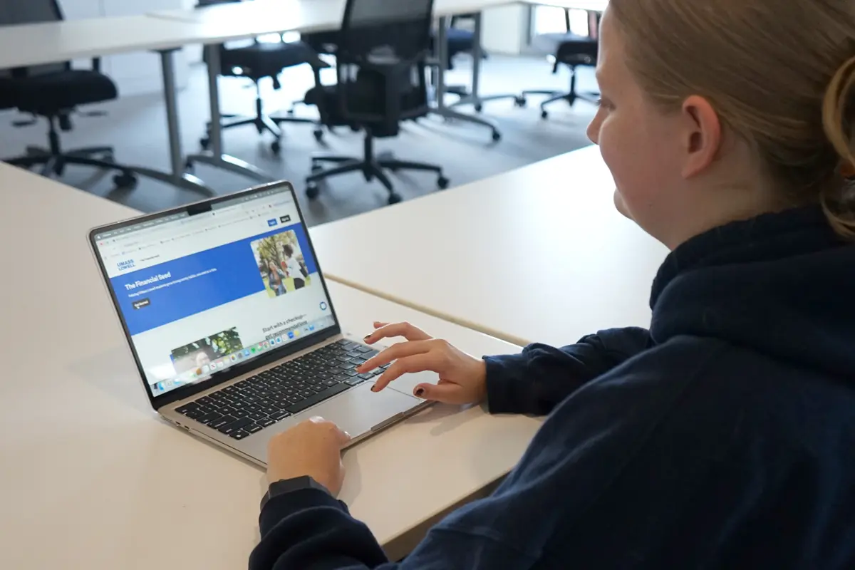 A young woman works on a laptop at a table.