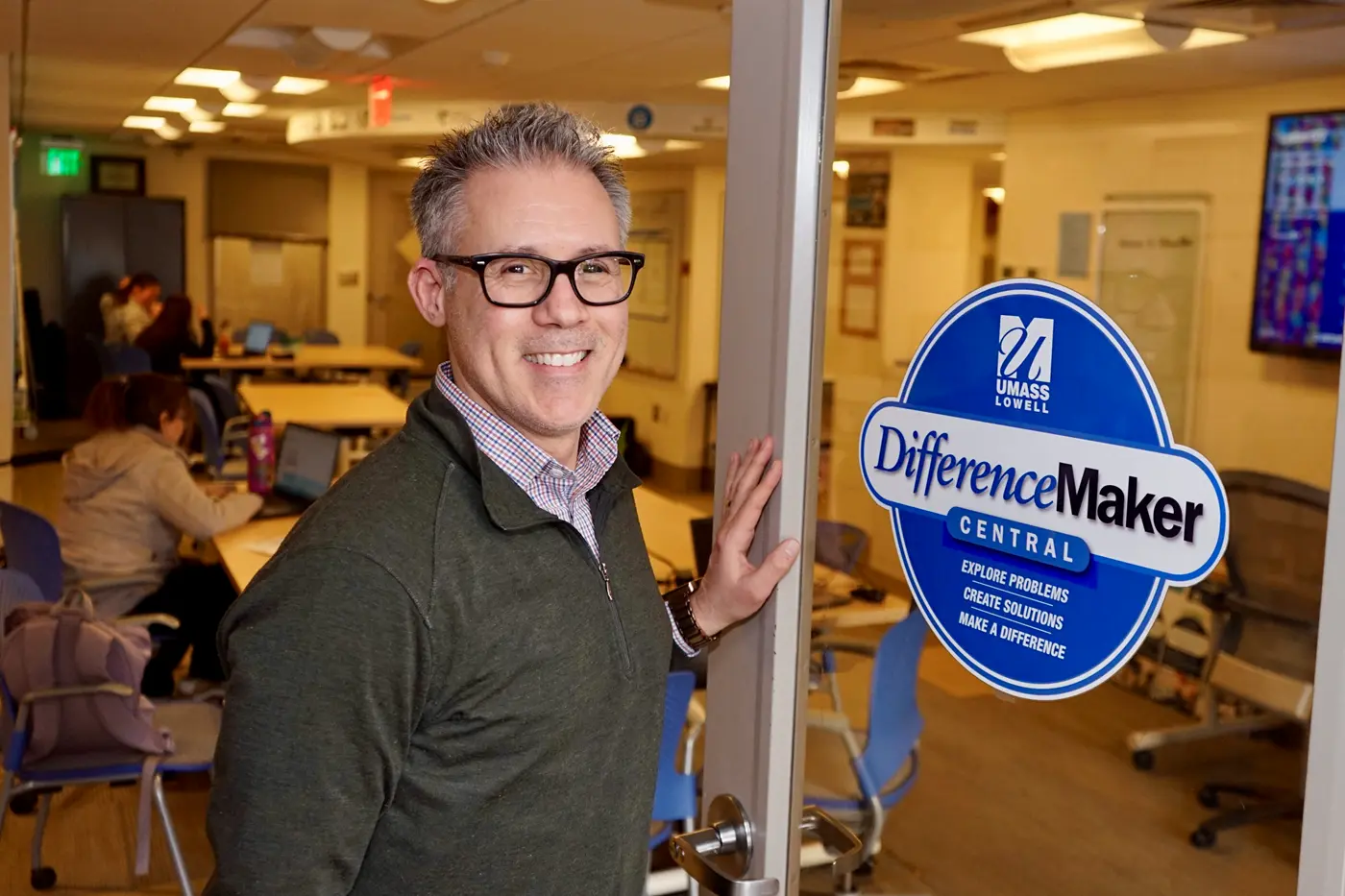 Richard Juknavorian smiles holding open the door to DifferenceMaker Central.  