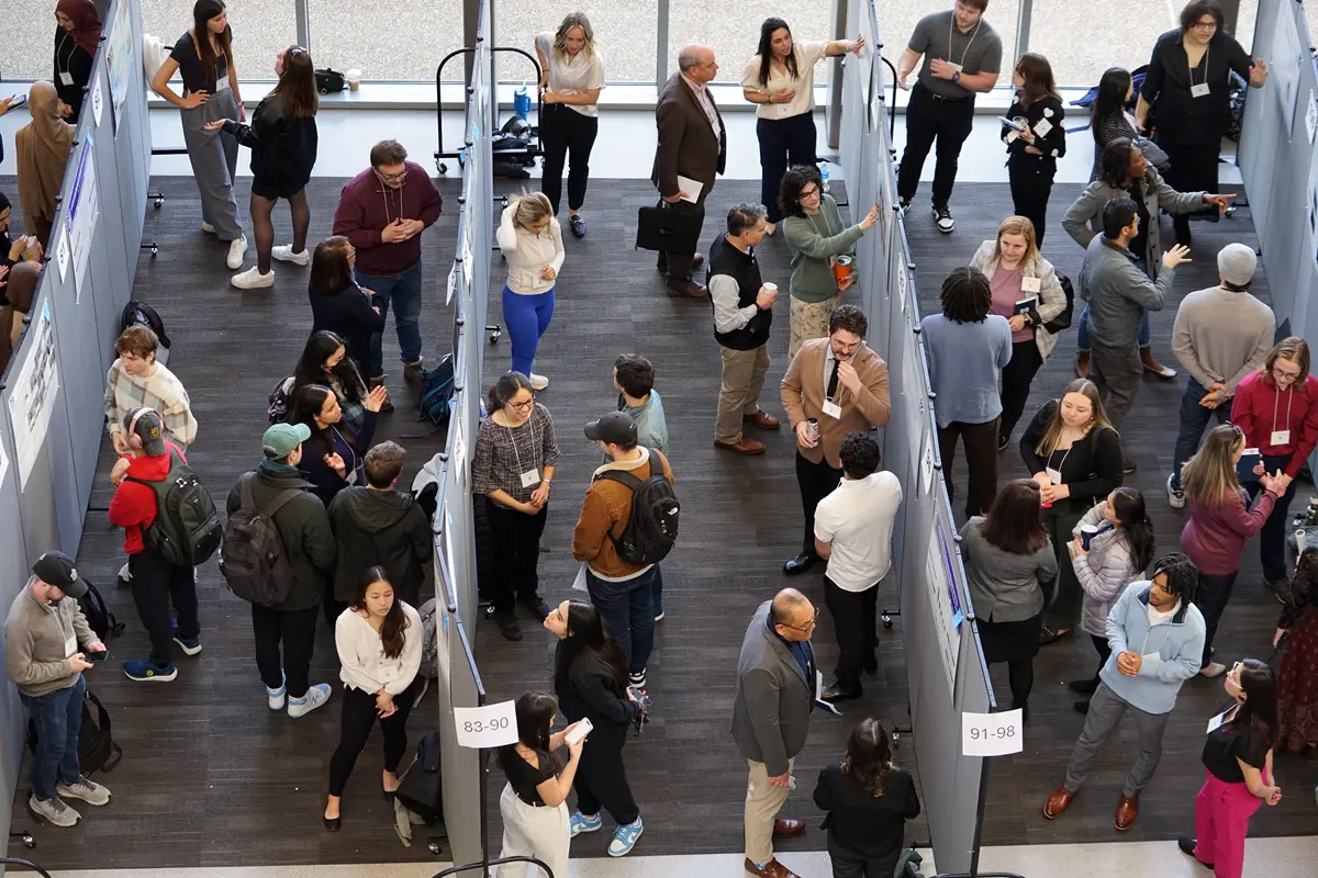 An overhead view of people presenting their research posters to guests in the lobby of a building.