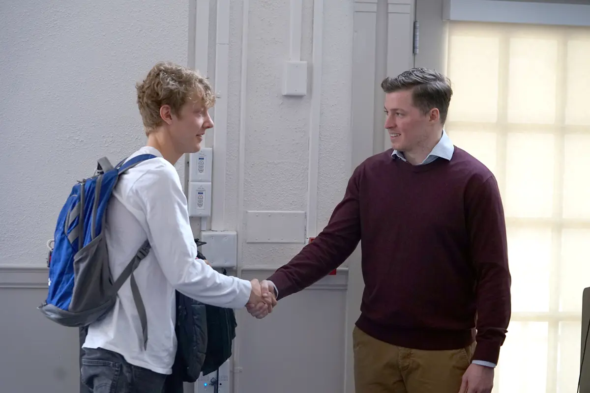 Two people shake hands in a room.