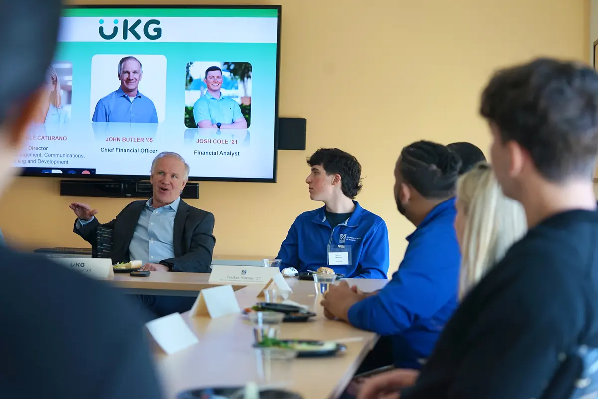 A group of people sit around tables in a conference room.