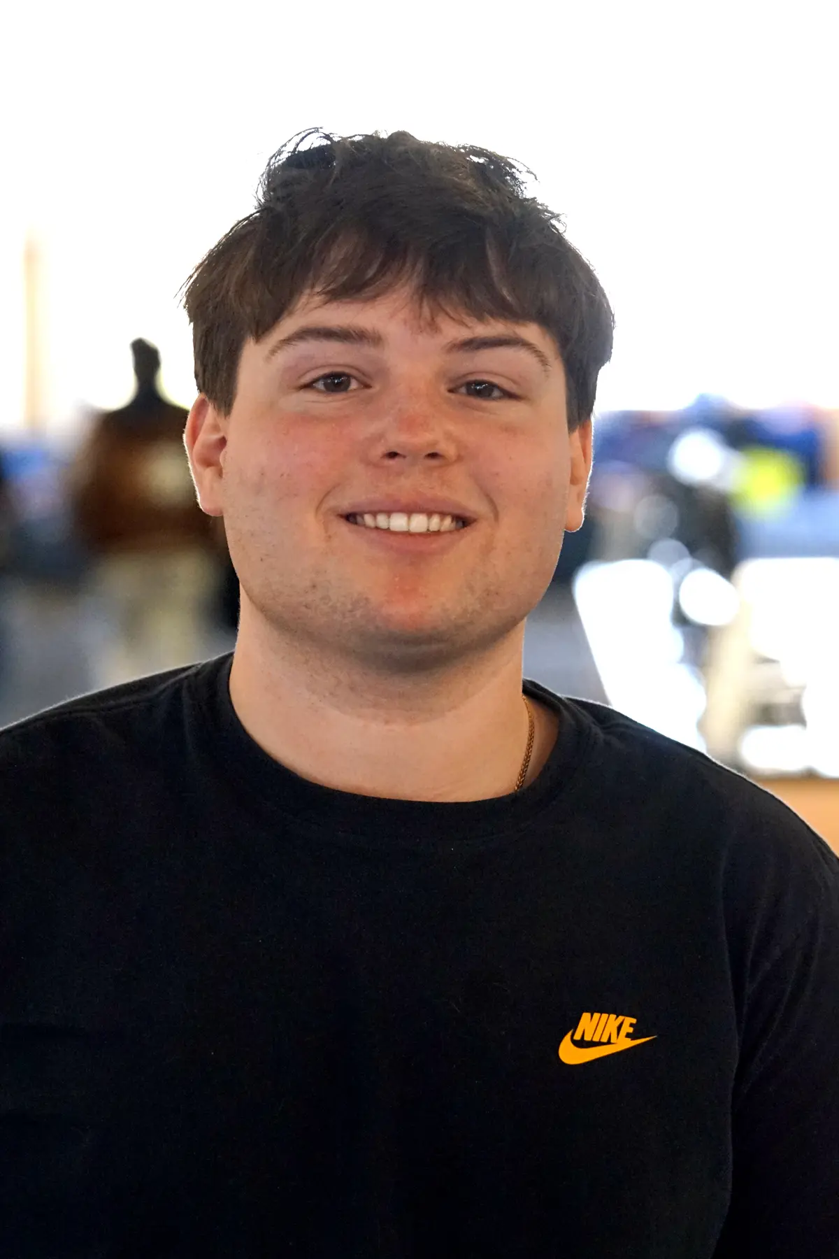 A person in a black sweatshirt poses for a photo against a bright backdrop.