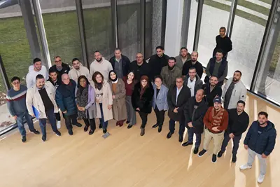 Two dozen people pose for a group photo taken from above in a room.