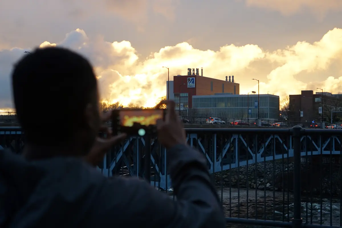 A person takes a photo of a dramatic sunset with their phone.