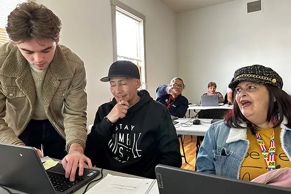 UML student Aidan Keefe helps Victor Coll and Marisol Merced learn how to set up a Zoom meeting