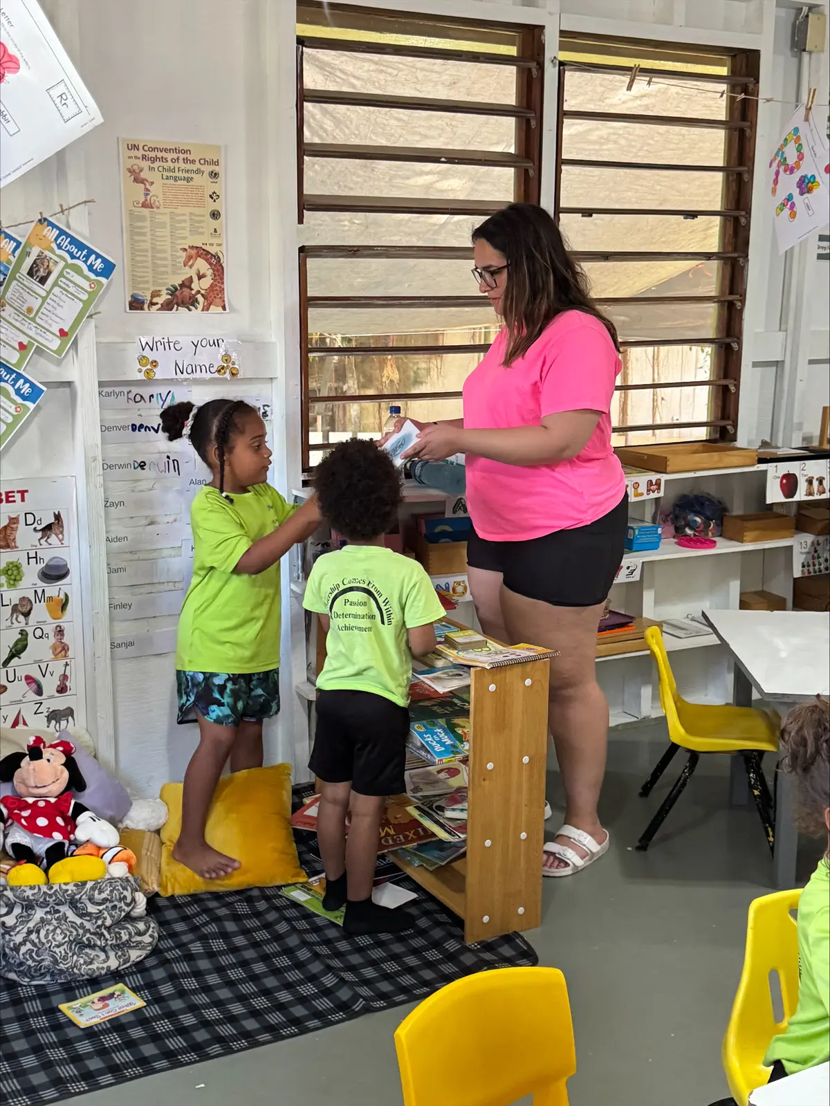 Amya Ortiz with two young children in a classroom at Placencia Elementary School