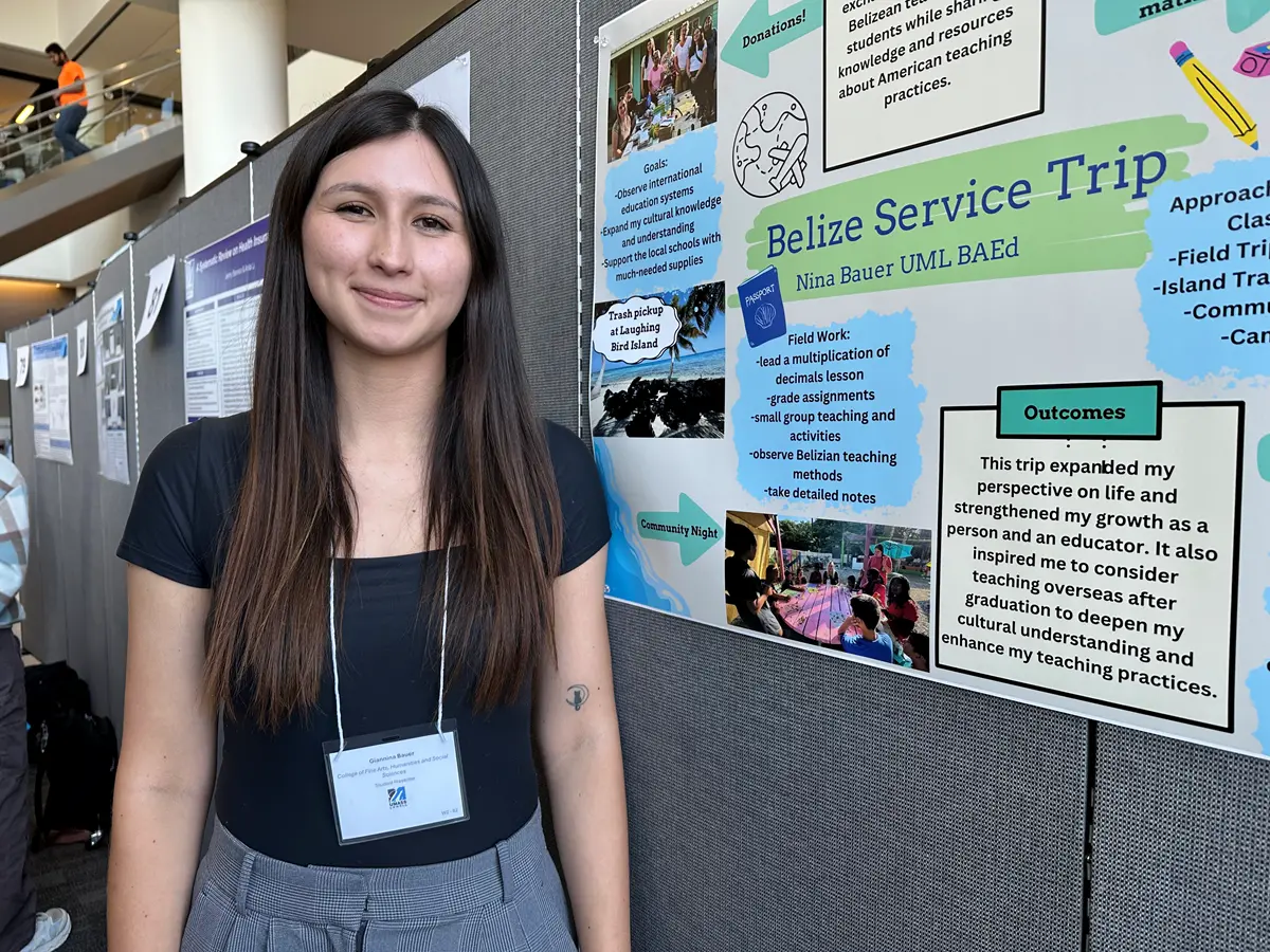 Giannina Bauer stands beside a poster about study abroad in Belize