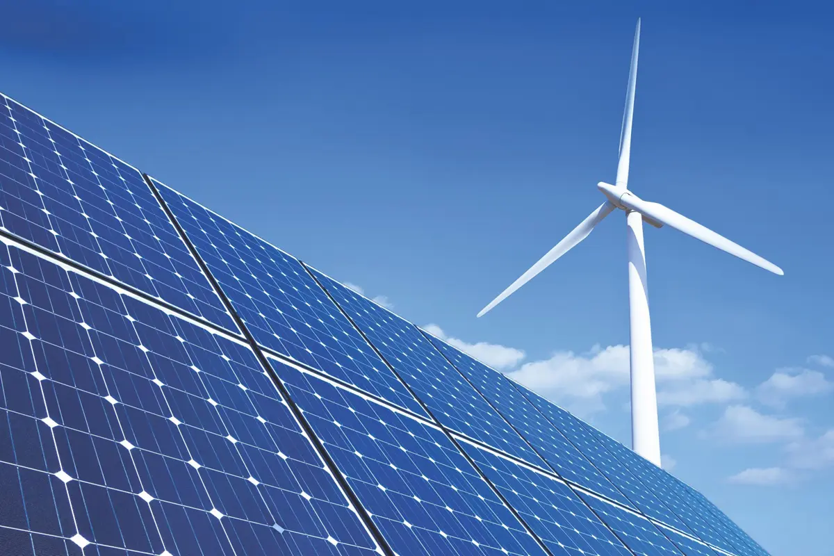 Wind turbine and solar panels outside on a clear and sunny day.