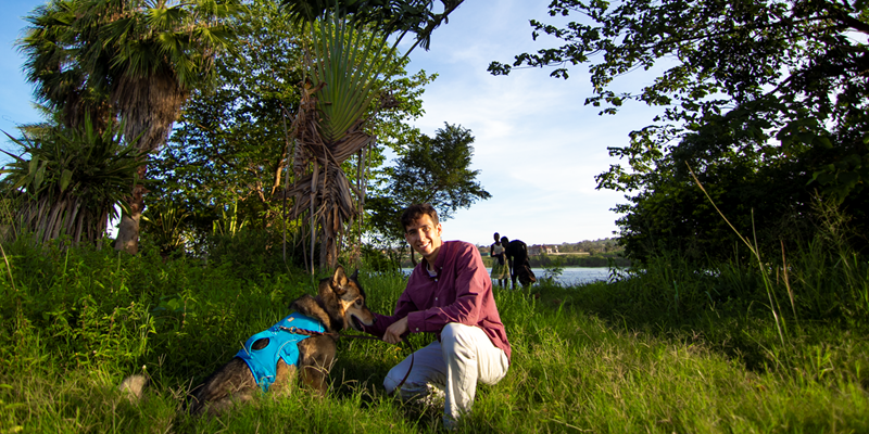 Evan Dingle poses in Uganda where he works with Ekisa Ministries with Tia, a retired sled dog he adopted who can serve as a loving bridge to the children and families