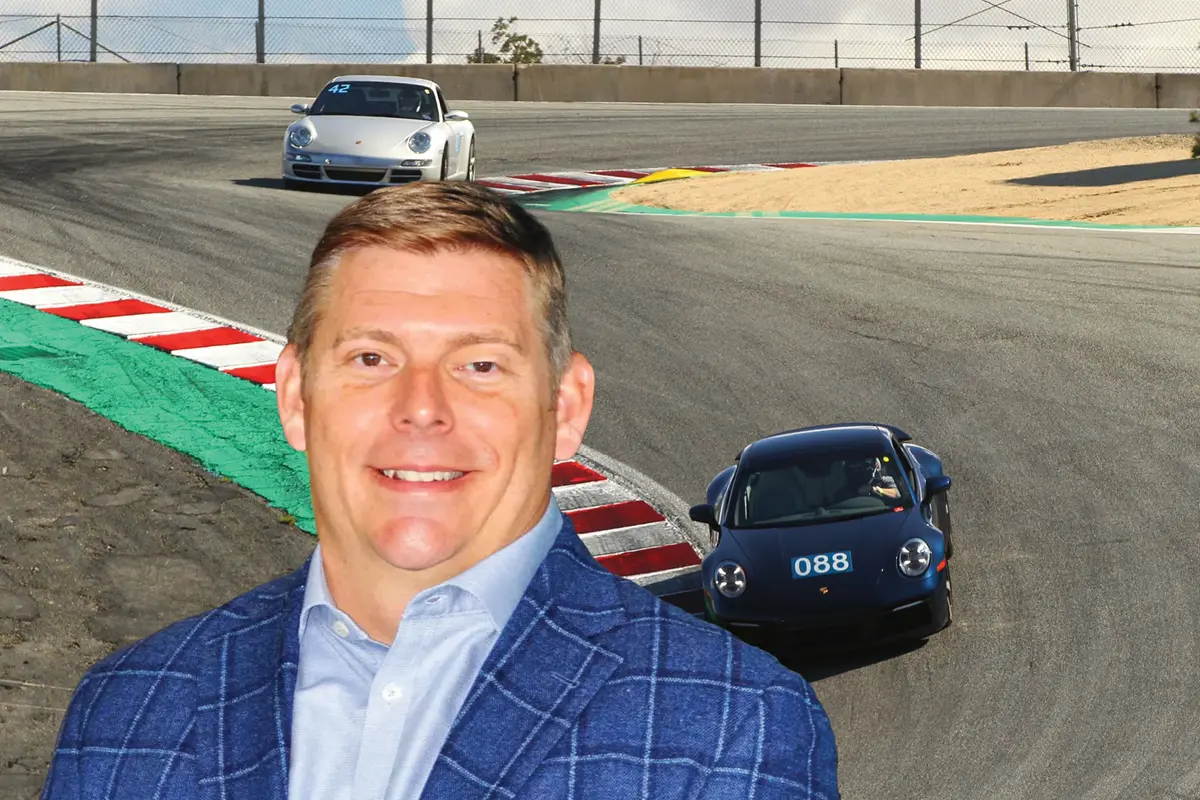 Mike Musgnug with race cars on a racetrack in the background.