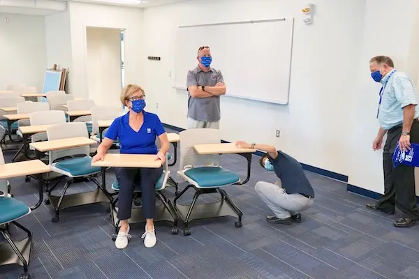 Chancellor Jacquie Moloney sits in a classroom desk