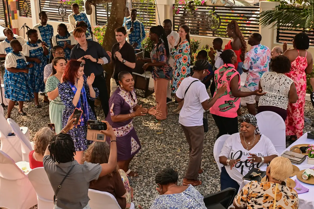 A large group of people dance in a circle during a party outside.