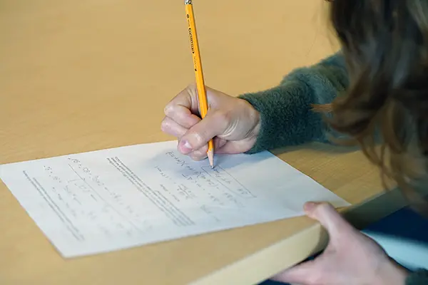 A person writes on a chemistry exam