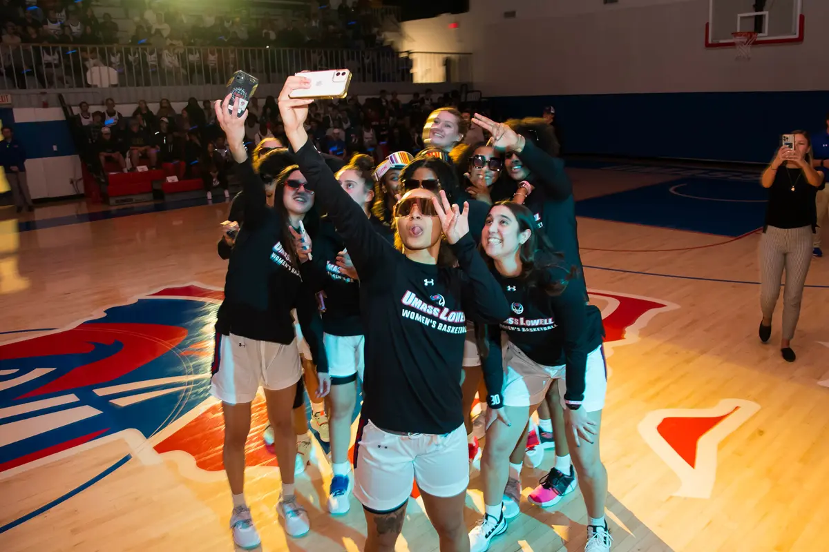 Young women dressed in black T-shirts and sunglasses take a group selfie.