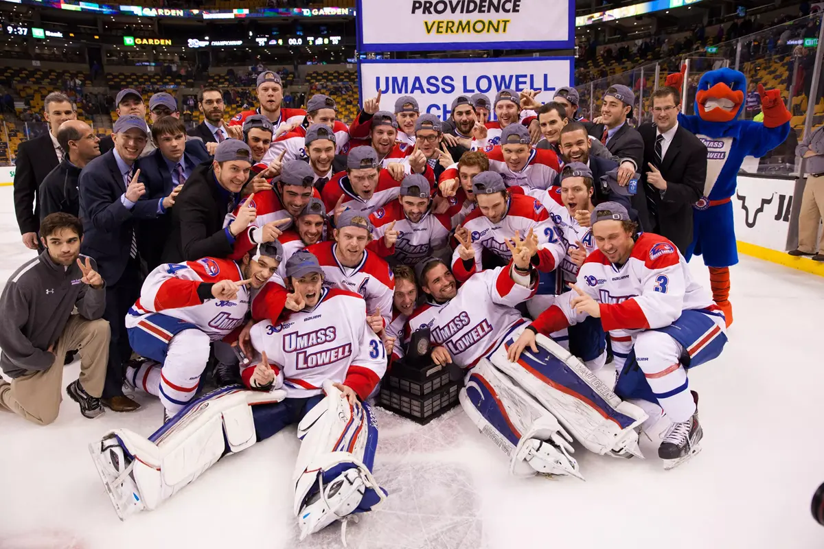 A men's college hockey team poses for a group photo on the ice.