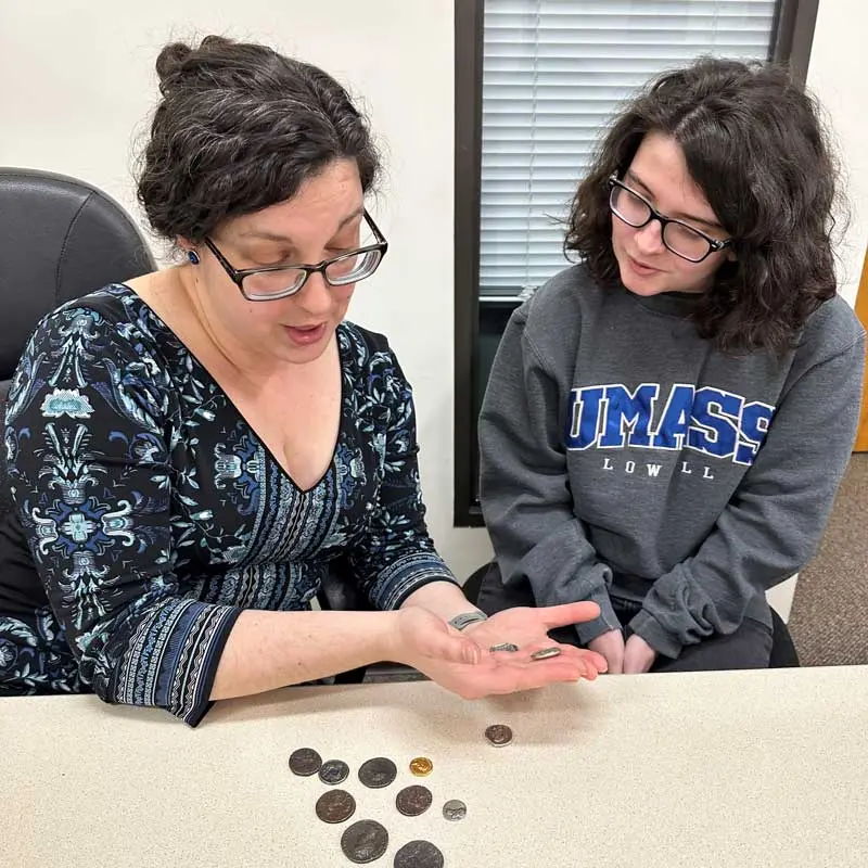 Two people view and discuss historical coins.