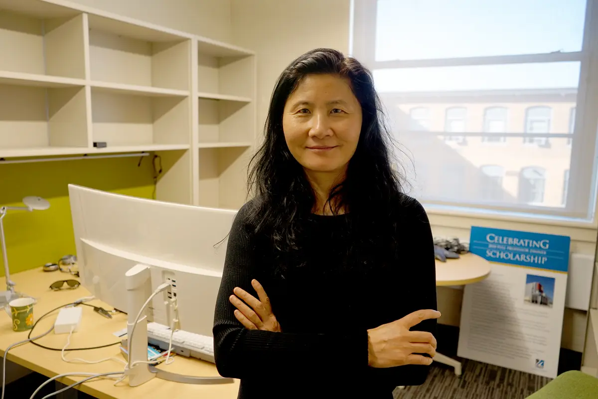 A woman with dark hair wearing a dark top poses for a photo in an office.