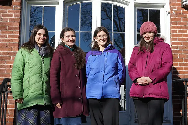 From left, sisters Eleanora, Regina, Margaret and Rose Peters bundled up on a stairway outside Allen House, home of the UMass Lowell Honors College