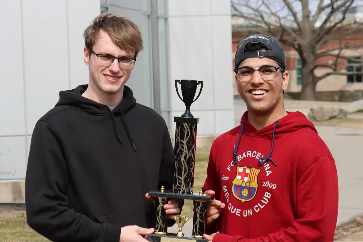 Two students hold a trophy.