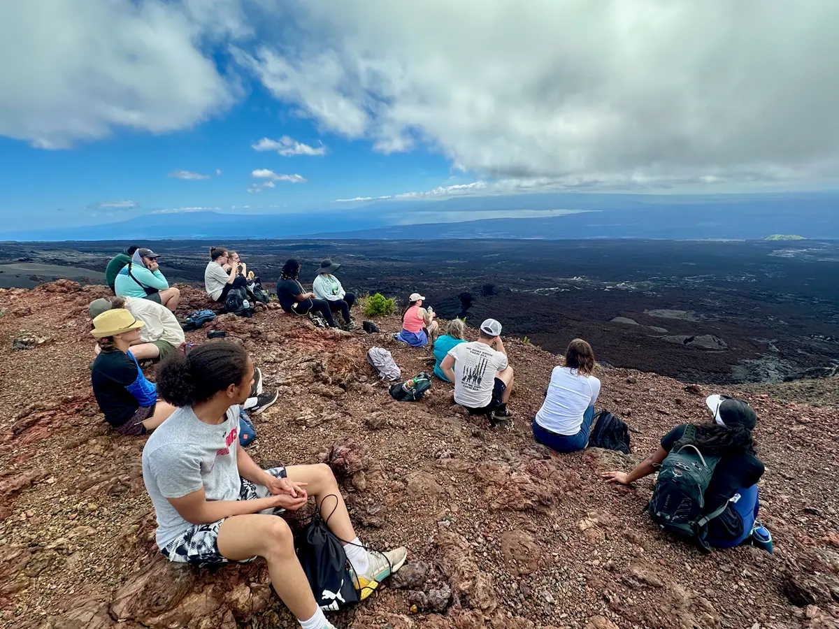 A dozen college students admire the view from the top of a caldera.