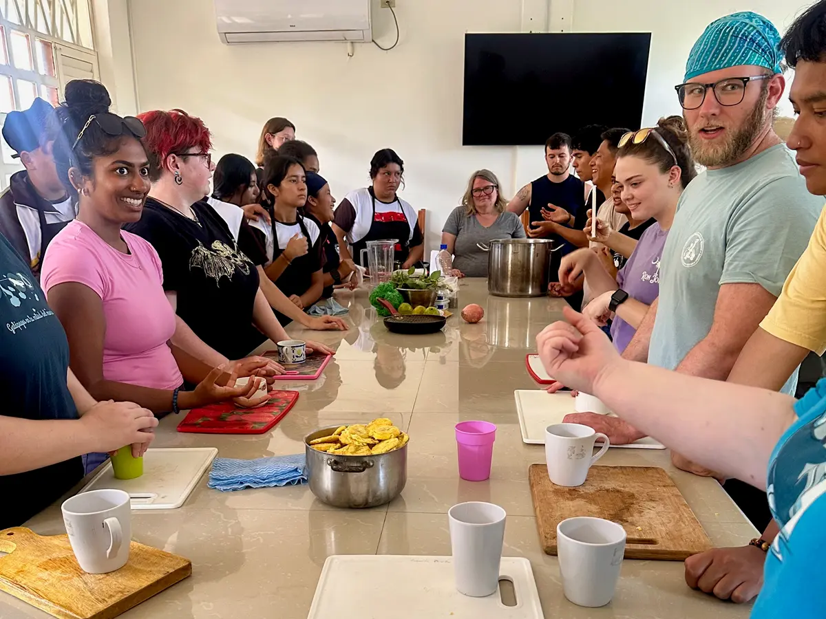 A dozen college students stand around a table during a cooking lesson.