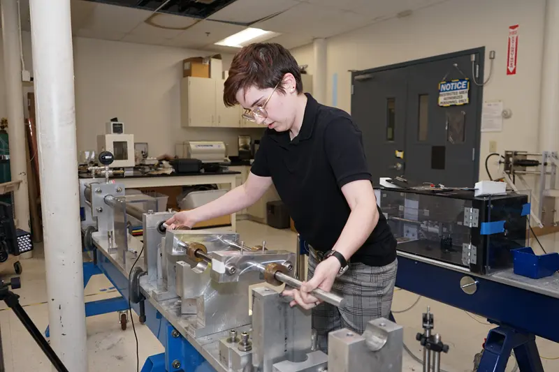 Kay Wojtowicz uses a split-Hopkinson pressure bar in UMass Lowell's mechanical engineering research lab.