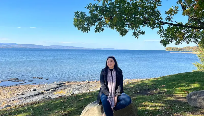 Kristin Kahla seated on a rock outdoors with a lake behind her