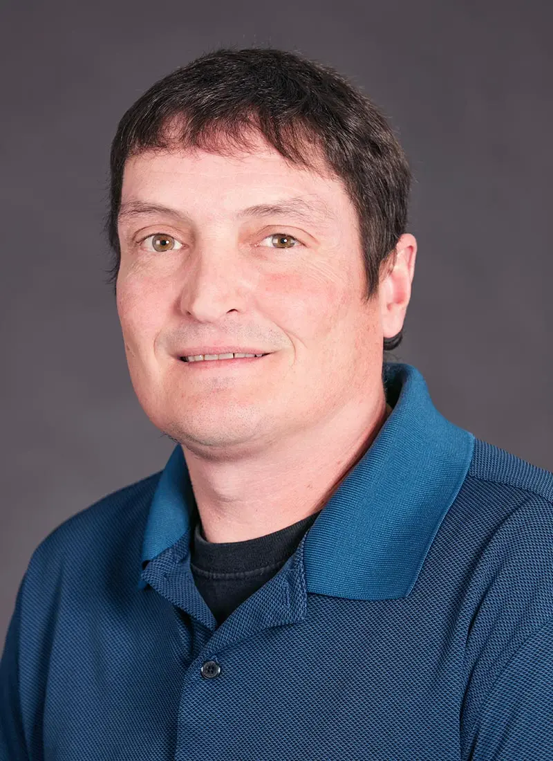 Steven Lessard wearing a blue shirt and smiling at the camera.