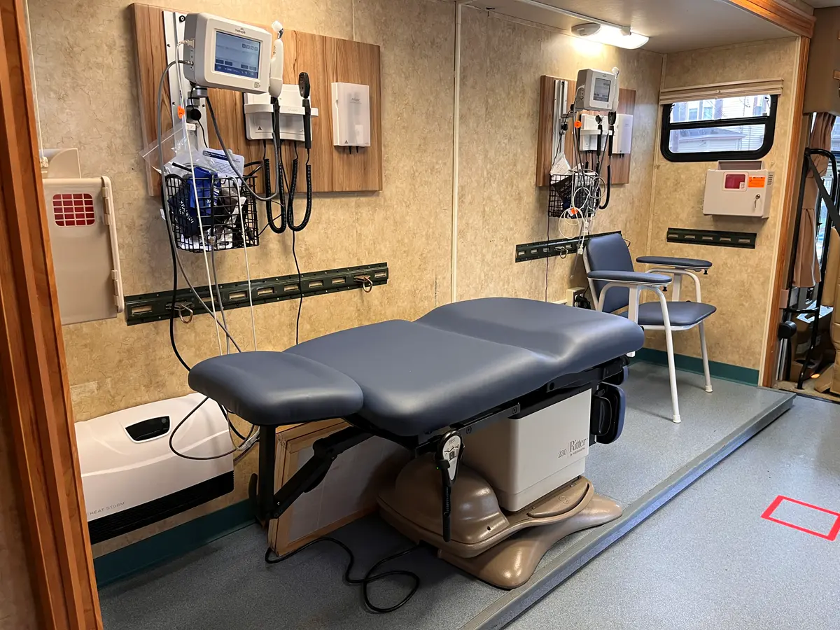 Inside view of mobile health unit with chair, exam table and monitors