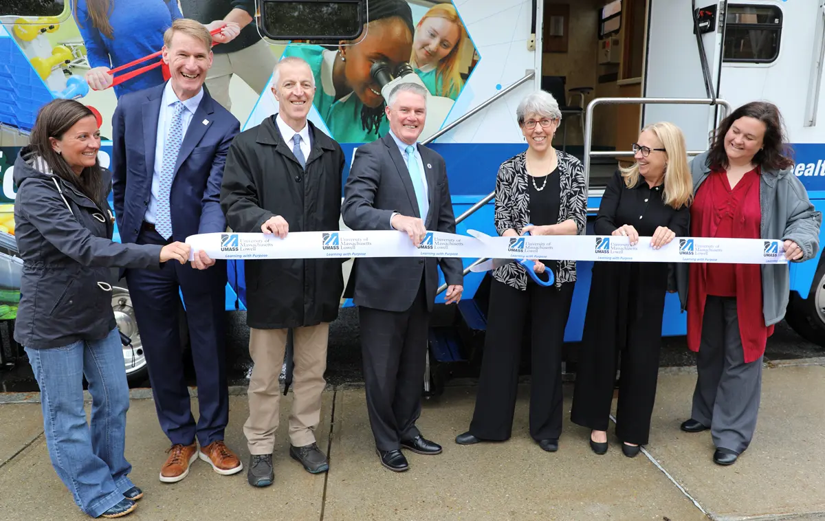 People standing in front of mobile health unit cutting ribbon