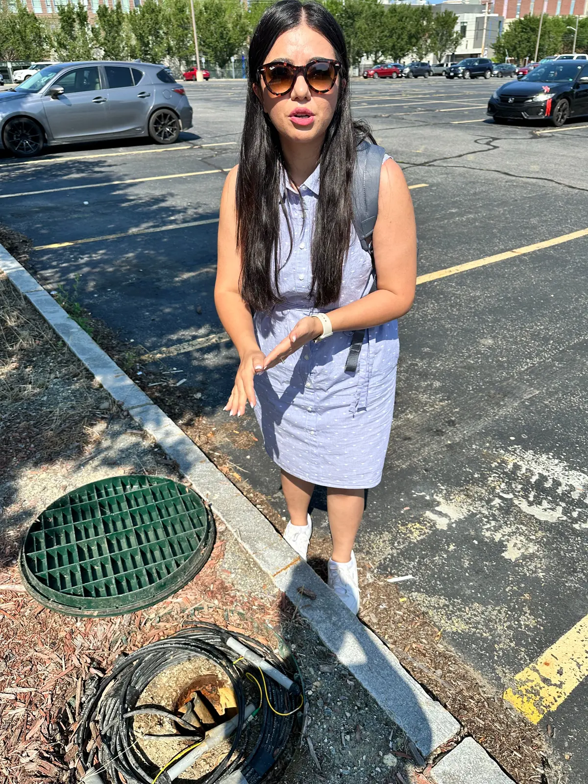 Mahsa Ghandi points out monitoring equipment in a test geothermal borehole in a parking lot