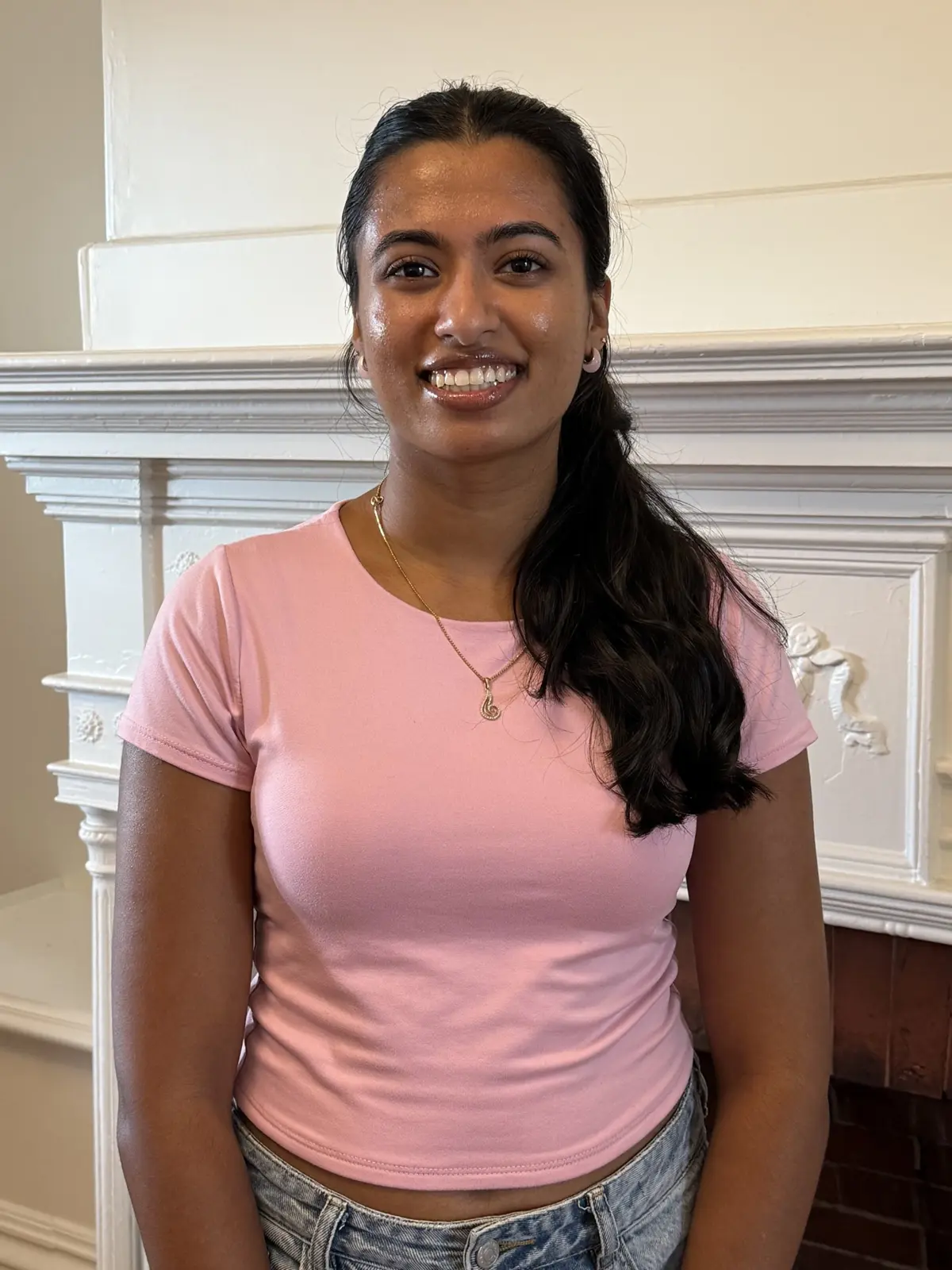 Megha standing in front of fireplace.