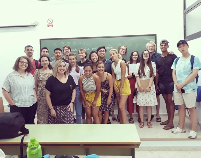 Melissa DiPano poses with a large group of students in a classroom.