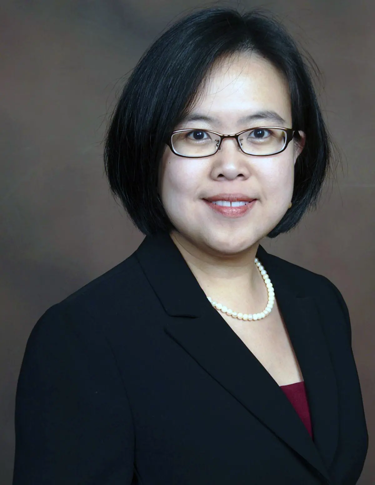A person wearing glasses and a dark blazer posing for a photo.
