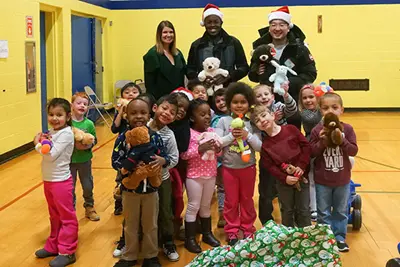 Students Ralph Saint Louis ’18 (at rear, center) and Qin “Sal” Li distributing stuffed animals to children at the Lowell YMCA Preschool.
