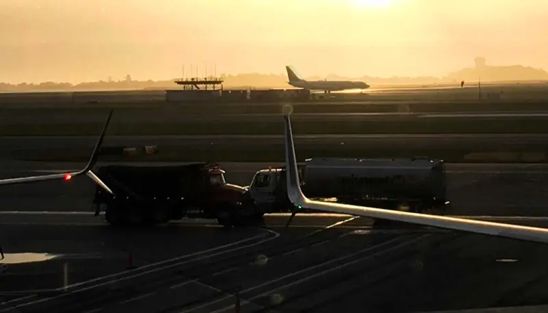 Plane and trucks on an airport runway.