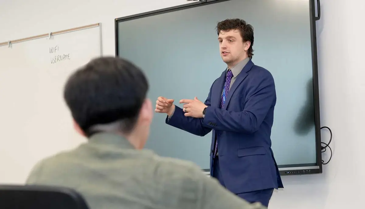 Sam DeLap delivers a presentation in front of a screen.