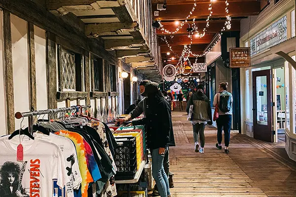 Two people look at records while two other people walk down a hallway lined with shops
