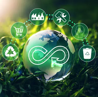 Circular economy graphic: globe in grass with circles above for recycling, shopping cart, factory building, hammer and wrench, gears inside head and trash can.