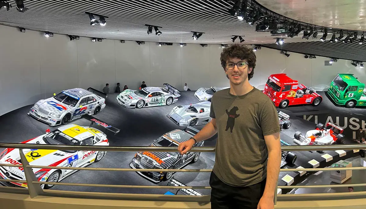 Teddy Lagrander stands in front of a display of cars at a museum.